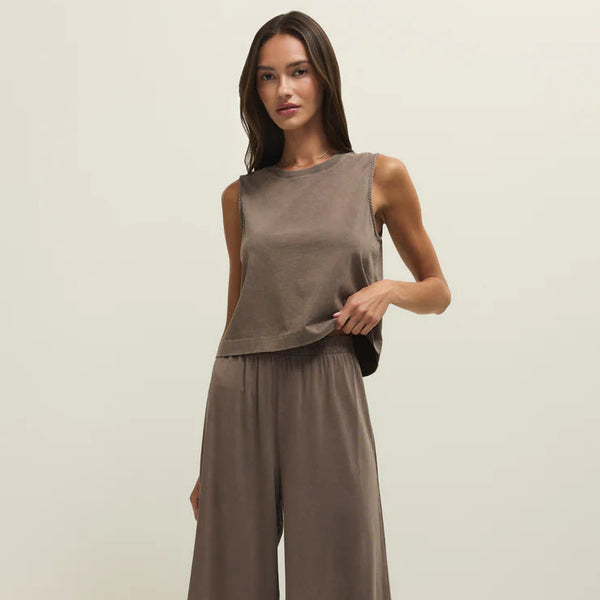 Woman wearing a brown sleeveless top and wide-leg pants on a white background