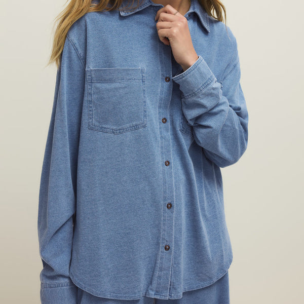 Woman wearing a blue denim shirt against a plain background