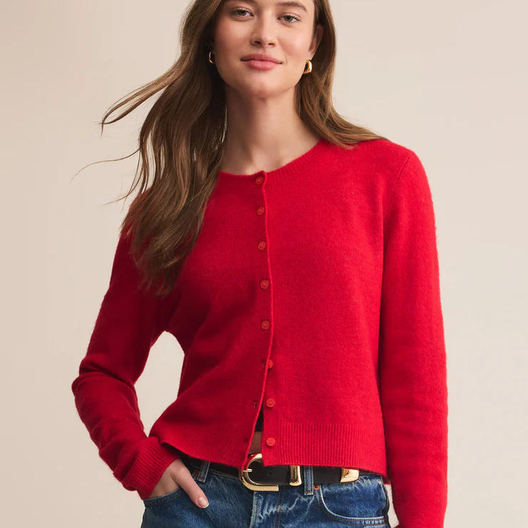 Woman wearing a red cardigan and blue jeans on a beige background