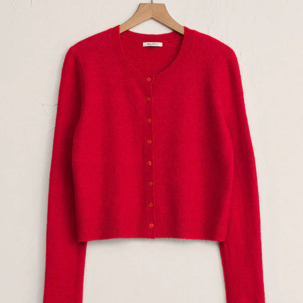 Red cardigan on a wooden hanger against a beige background