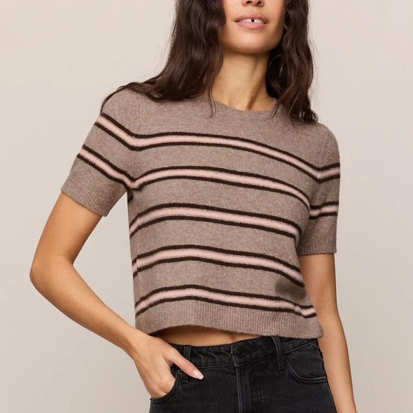 Woman wearing a striped sweater and black jeans against a plain background