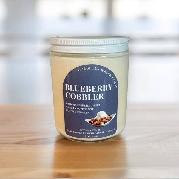 Jar of 'Blueberry Cobbler' candle with a label on a wooden surface