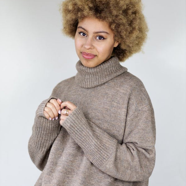 Woman wearing a beige sweater against a white background