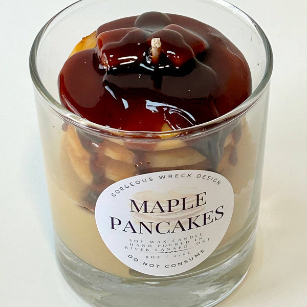 Candle in a glass jar labeled 'Maple Pancakes' on a white background
