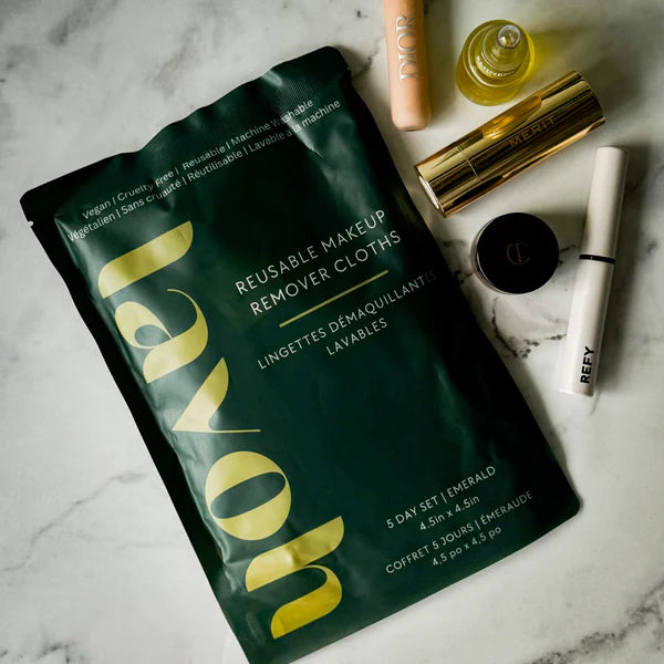 Reusable makeup remover cloths packaging on a marble surface with cosmetic products.