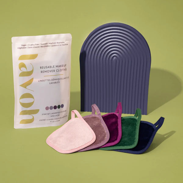 Reusable makeup remover cloths with packaging and a purple holder on a green background