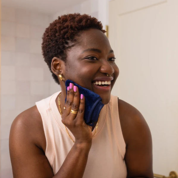 Woman applying a blue facial scrubber to her face in a bathroom setting