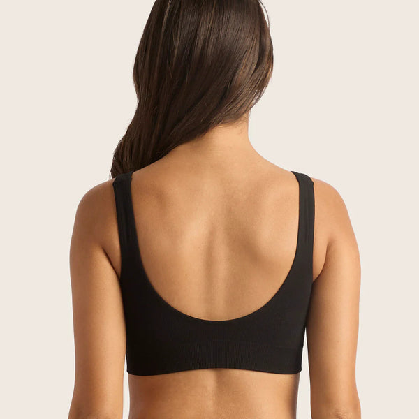 Person wearing a black sports bra on a beige background