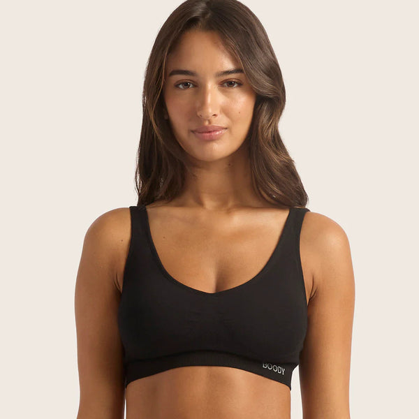 Woman wearing a black sports bra with a visible brand logo on a light pink background