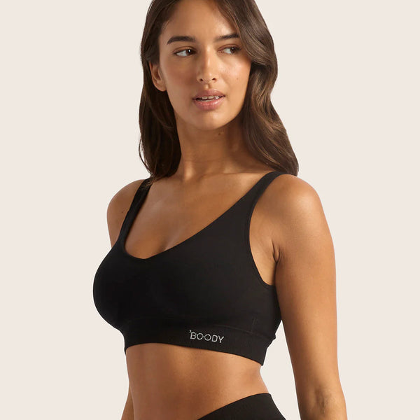 Woman wearing a black sports bra and leggings with 'boody' branding on a neutral background