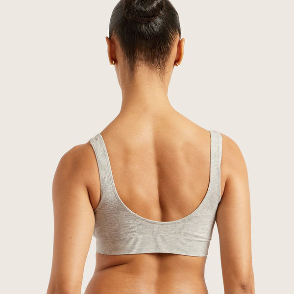 Woman wearing a gray sports bra and leggings on a light background