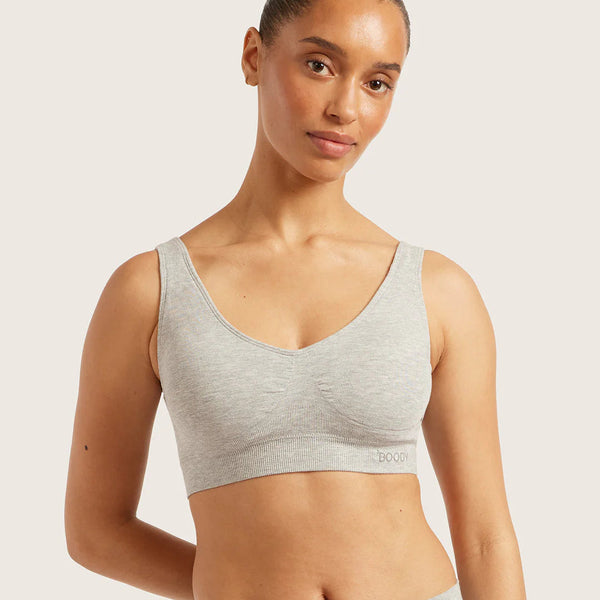Woman wearing a gray sports bra and leggings on a light background