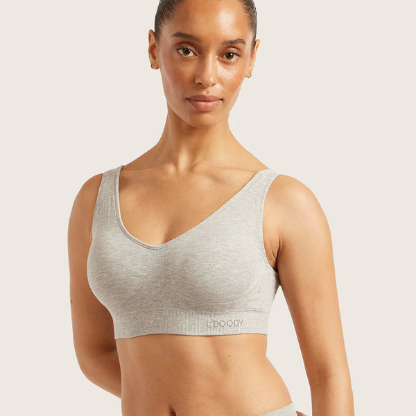 Woman wearing a gray sports bra and leggings on a light background