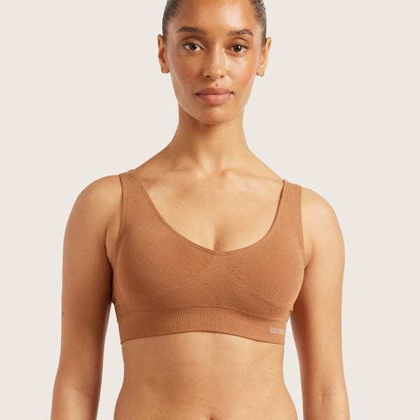 Woman wearing a brown sports bra and leggings on a light background