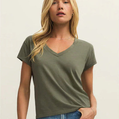 Woman wearing a green t-shirt and blue jeans on a plain background