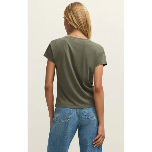 Person wearing a green t-shirt and blue jeans on a plain background