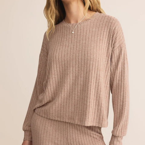 Woman wearing a ribbed beige long-sleeve top and pants on a plain background